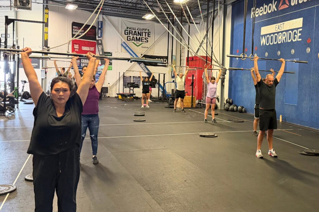 Members practising an overhead movement with PVC pipes during a coached CrossFit class at Cristini Athletics