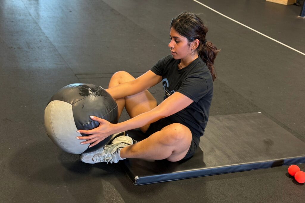 Cristini Athletics member doing a medicine ball sit-up on a mat during training