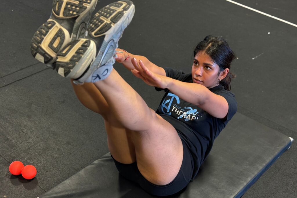 Member performing a V-up core exercise on a mat at Cristini Athletics
